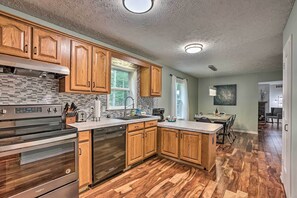 A modern kitchen with wooden cabinets, stainless steel appliances, and a herringbone wood floor. - Charming Pentwater Home w/ Fire Pit & Yard! (Pentwater)