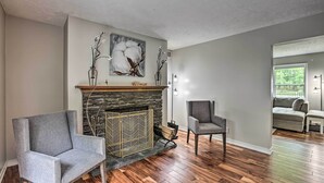 Una sala de estar con chimenea de piedra, dos sillones y un sofá.