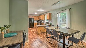 Una cocina moderna con armarios de madera, una isla central y un comedor con mesa y sillas de madera.