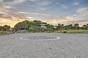 A beach with a lifeguard tower, a circular stone pattern, and a house with a sloped roof. - Central Venice Apartment w/ Balcony, Walk to Beach (Venice)