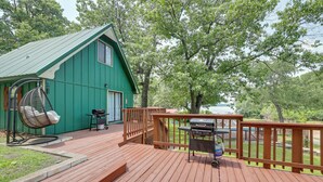 Een groene woning met een terras, een hangstoel en een barbecue.