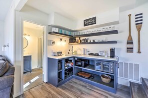 A compact kitchen with built-in appliances, open shelving with glassware, and a coffee station.