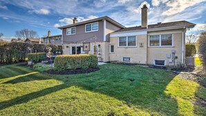 A two-story house with a well-maintained lawn and a small garden area. - Elegant Mount Prospect Home w/ Fire Pit! (Mount Prospect)