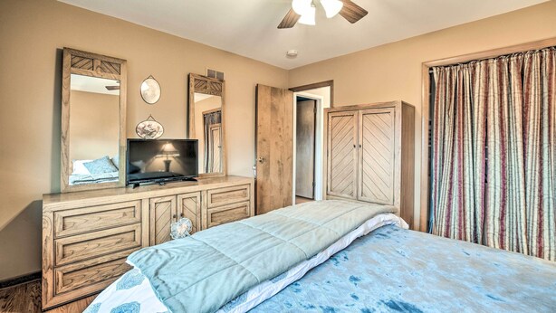A bedroom with a bed, a dresser, a television, a ceiling fan, and a wardrobe. - Elegant Mount Prospect Home w/ Fire Pit! (Mount Prospect)