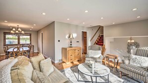 A spacious living room with a large sofa, armchairs, a coffee table, and a dining area with a wooden table and chairs. - Elegant Mount Prospect Home w/ Fire Pit! (Mount Prospect)