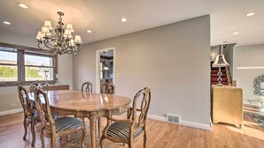 A dining room with a wooden table and chairs, a chandelier, and a view through a window. - Elegant Mount Prospect Home w/ Fire Pit! (Mount Prospect)