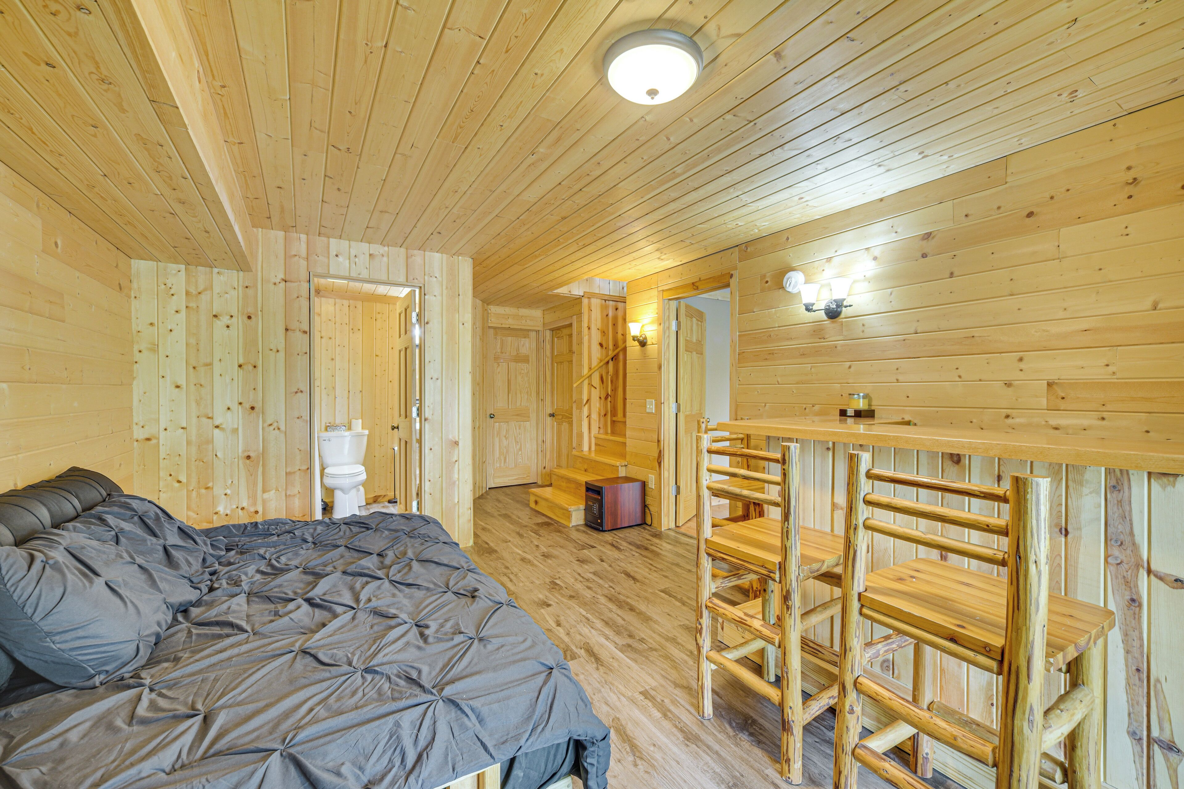 A wooden cabin room with a bed, a wooden table, and a chair.