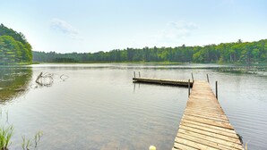 A wooden dock extending into calm water with a forested shoreline in the background. - Four-season Lake Cabin w/ Canoe & Paddle Boat! (Gordon)