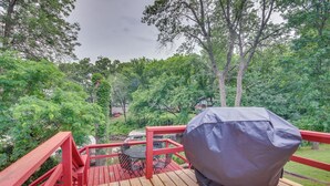 A wooden deck with a red railing, a covered grill, and a table with chairs. - Yard + 15' Boat Slip: Waterfront Grove Getaway (Grove)
