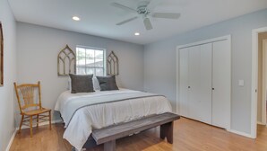 A bedroom with a bed, a wooden chair, a bench, a ceiling fan, and a wardrobe. - Yard + 15' Boat Slip: Waterfront Grove Getaway (Grove)