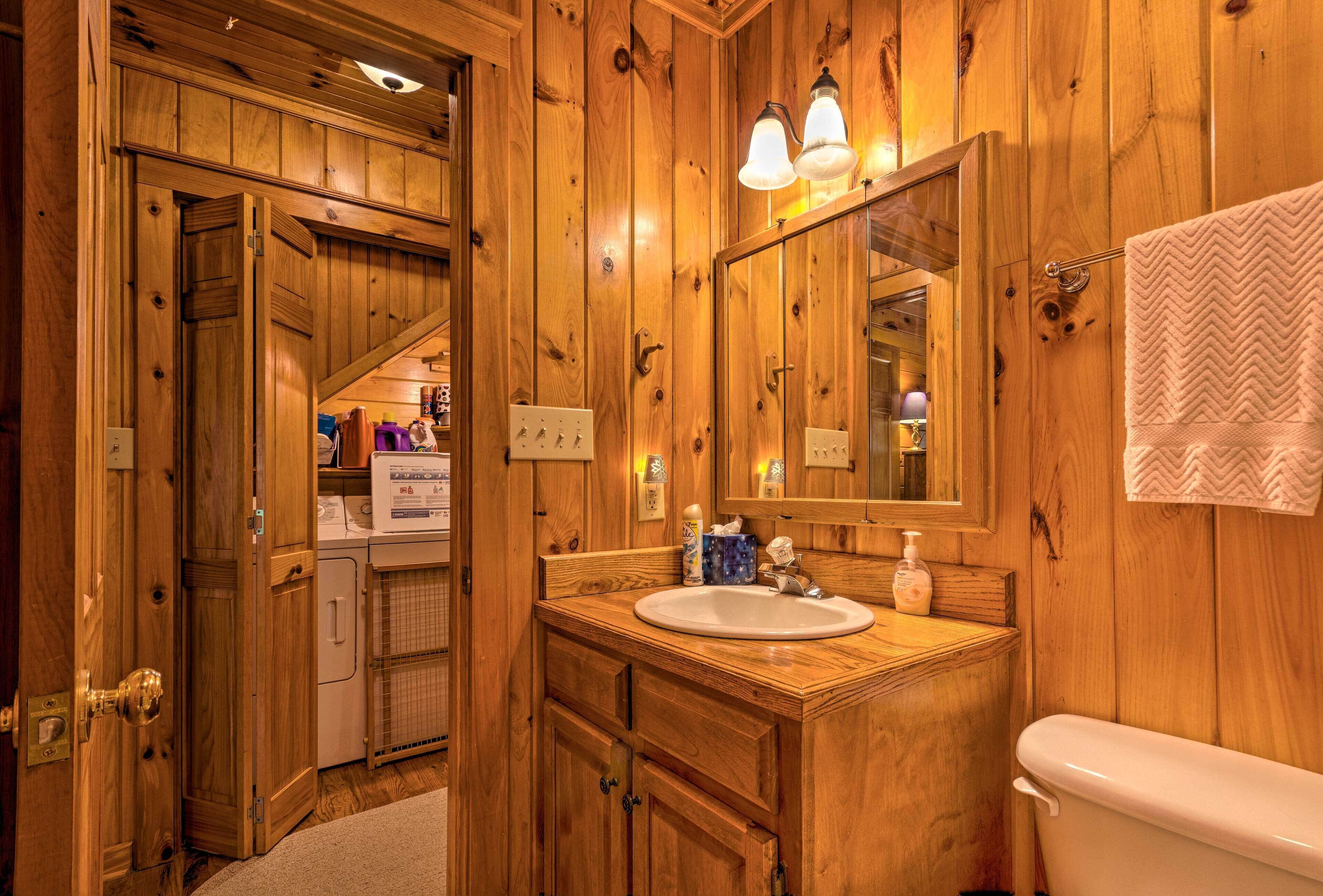 Un baño de madera con lavamanos, espejo y retrete.