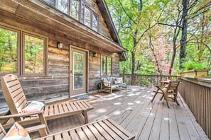 A wooden deck with outdoor furniture, including chairs and a table, overlooking a forested area. - Chic Brevard Cabin - Nature, Trails, & Water! (Brevard)