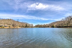 A calm lake with a forested shoreline and buildings in the background. - Chic Brevard Cabin - Nature, Trails, & Water! (Brevard)