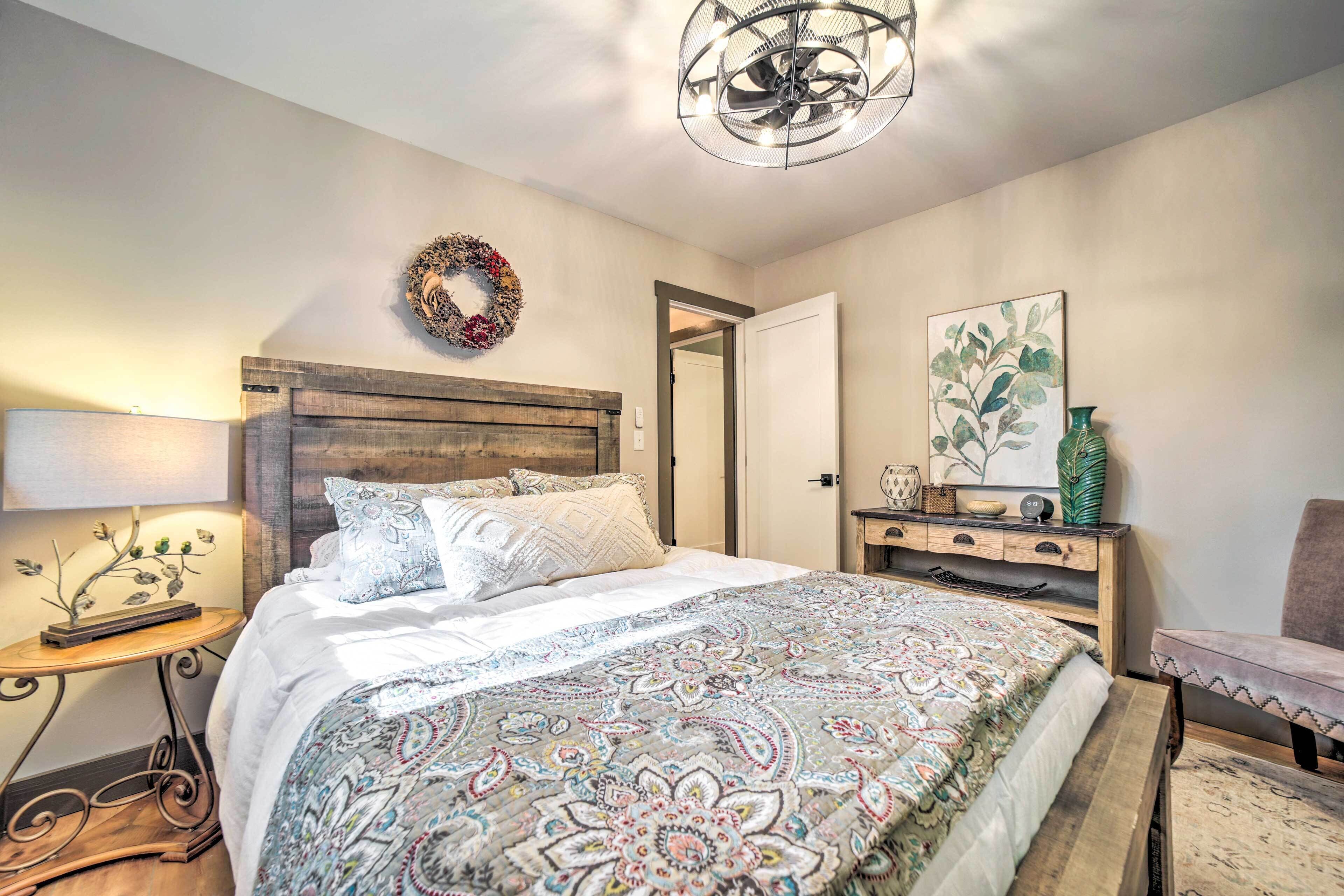 Una camera da letto con testiera in legno, copriletto a fantasia, comodino con lampada e un'asse di decorazione a parete.