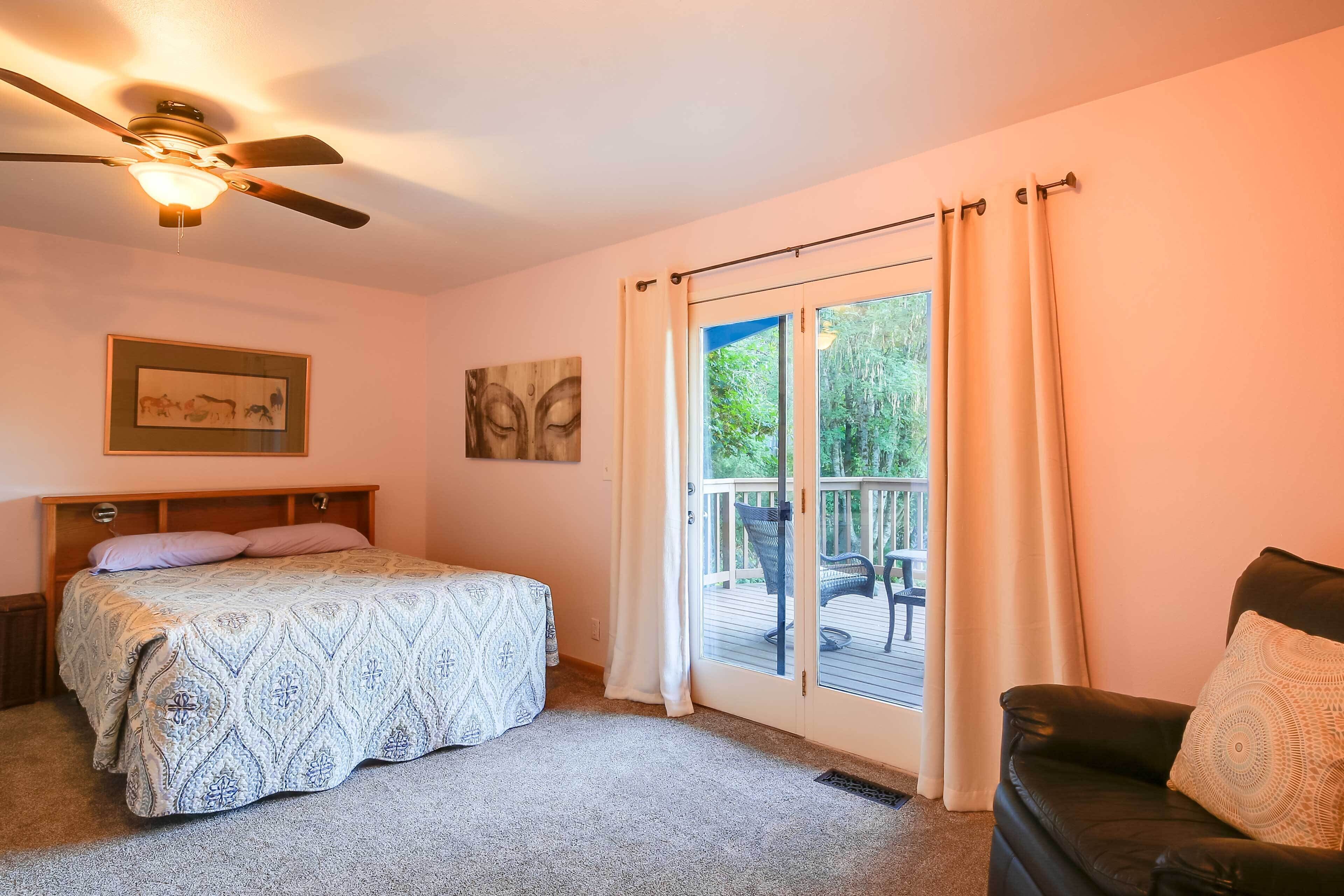 A bedroom with a bed, a ceiling fan, a sliding glass door to a balcony, and a chair.