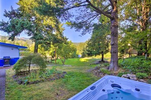 Un bain à remous dans un jardin luxuriant, avec un bâtiment bleu en arrière-plan.