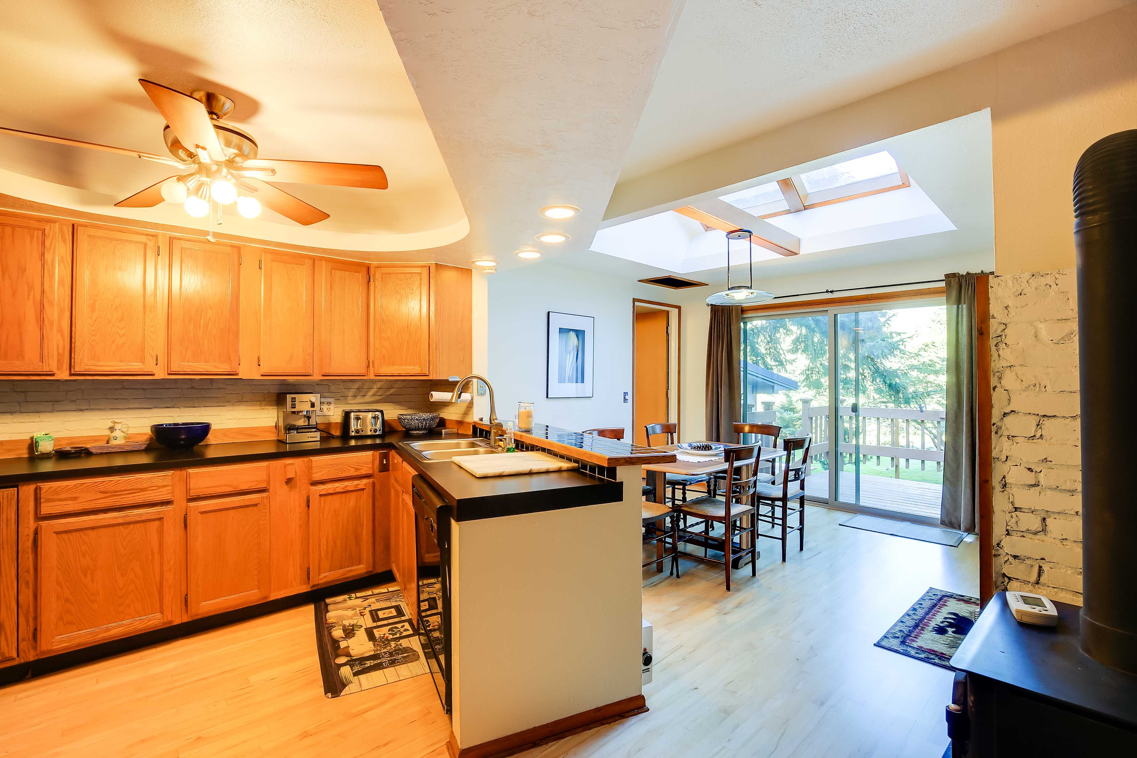 A modern kitchen with wooden cabinets, a central island, and a dining area with a view of the outdoors.