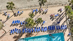 An aerial view of a beach with rows of blue lounge chairs and a swimming pool. - Oceanfront Myrtle Beach Condo w/ Balcony! (Myrtle Beach)
