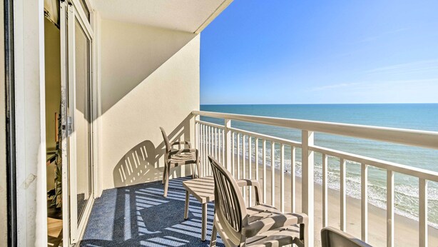 A balcony with a view of the beach, a table, and two chairs. - Oceanfront Myrtle Beach Condo w/ Balcony! (Myrtle Beach)