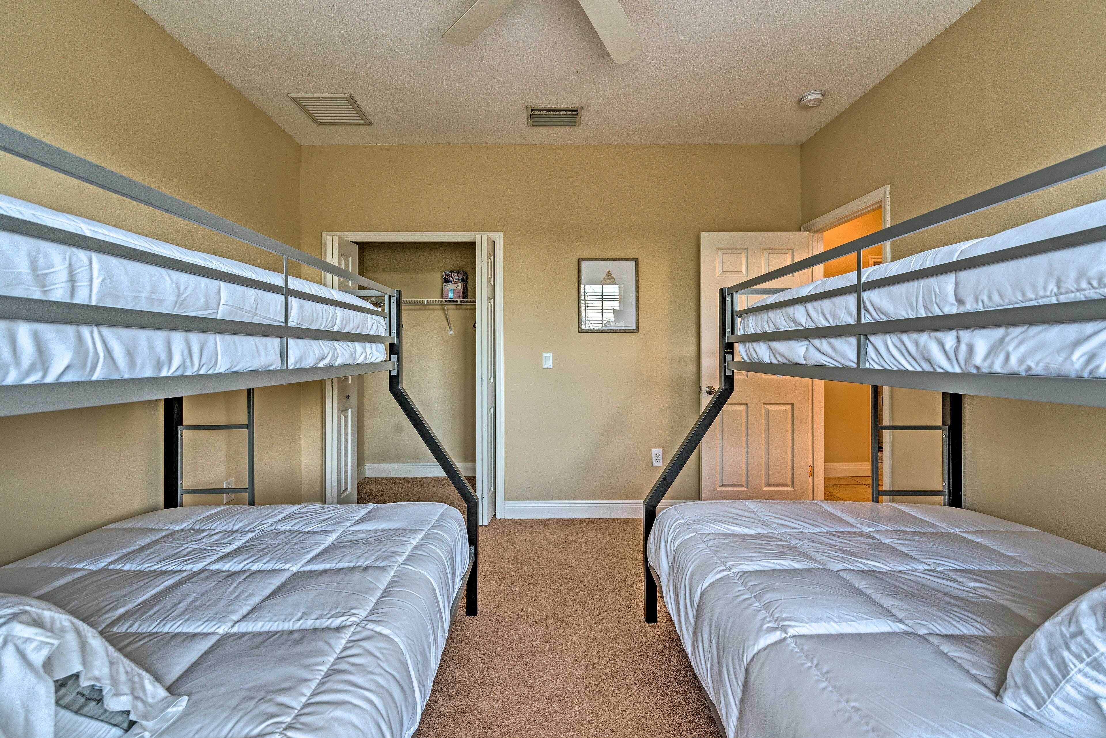 A room with bunk beds, a door, and a framed picture on the wall.