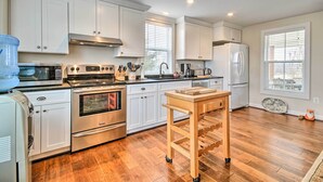 A modern kitchen with white cabinets, stainless steel appliances, and a wooden table.