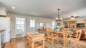 A spacious kitchen with wooden cabinets, a dining table with chairs, a built-in oven, and a large window with blinds.