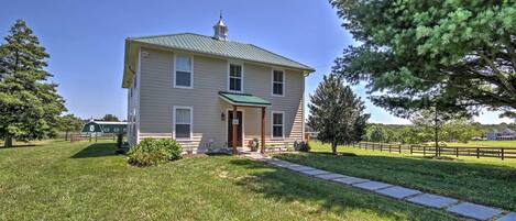 A two-story house with a green roof, a front porch, and a well-maintained lawn.