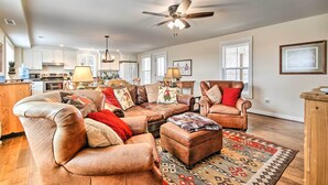 A spacious living room with a large sectional sofa, a leather armchair, and a patterned rug.