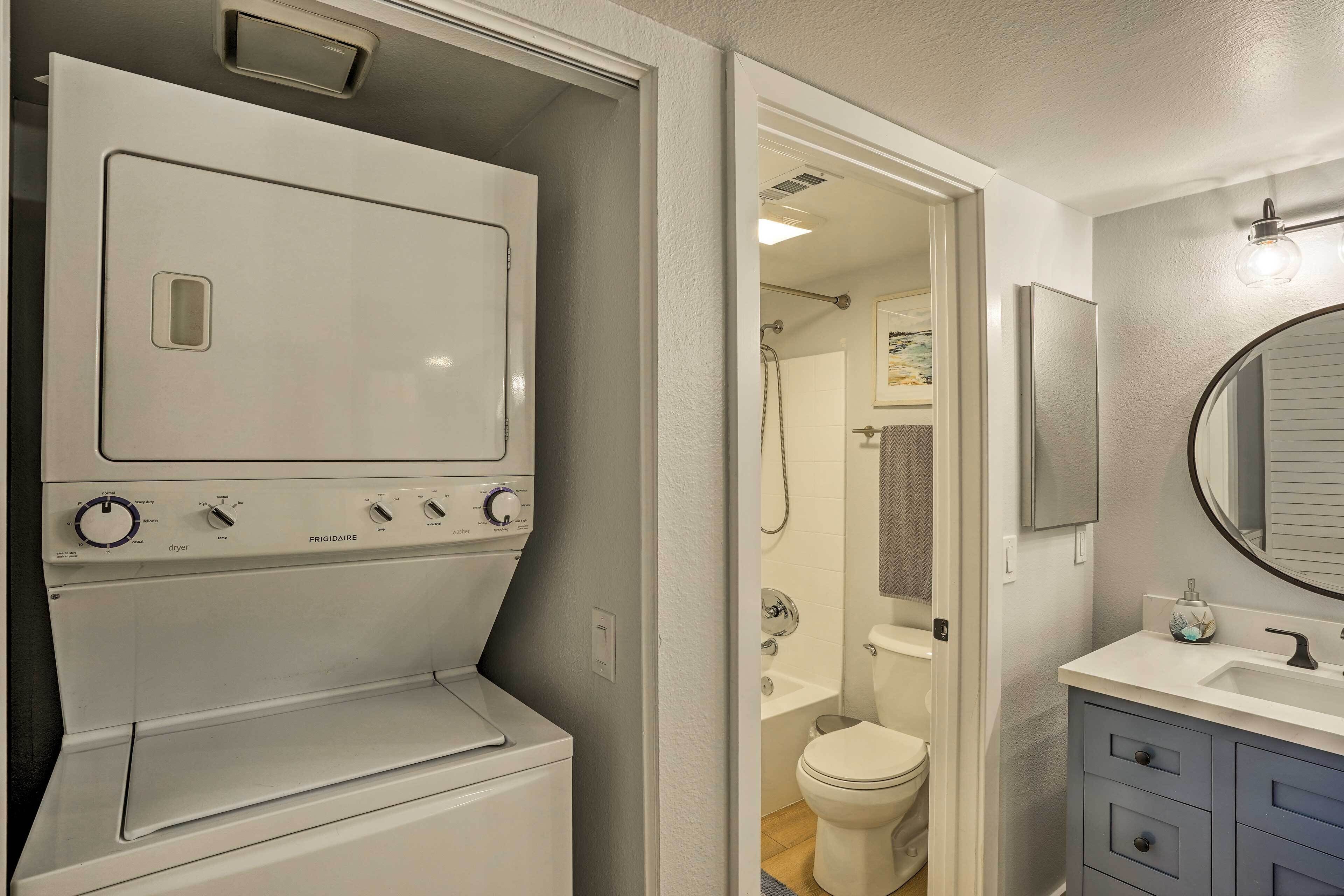 A compact laundry room with a Frigidaire washer and dryer, a bathroom with a toilet and shower, and a vanity with a mirror.