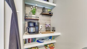A kitchen with shelves holding books, a coffee maker, and a potted plant. - Cozy Carolina Beach Condo w/ Ocean Views! (Carolina Beach)