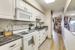 A kitchen with white cabinets, a stove, and a microwave.