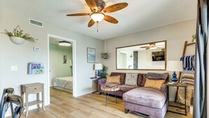 A living room with a ceiling fan, wooden flooring, a sofa, a coffee table, and a mirror. - Cozy Carolina Beach Condo w/ Ocean Views! (Carolina Beach)