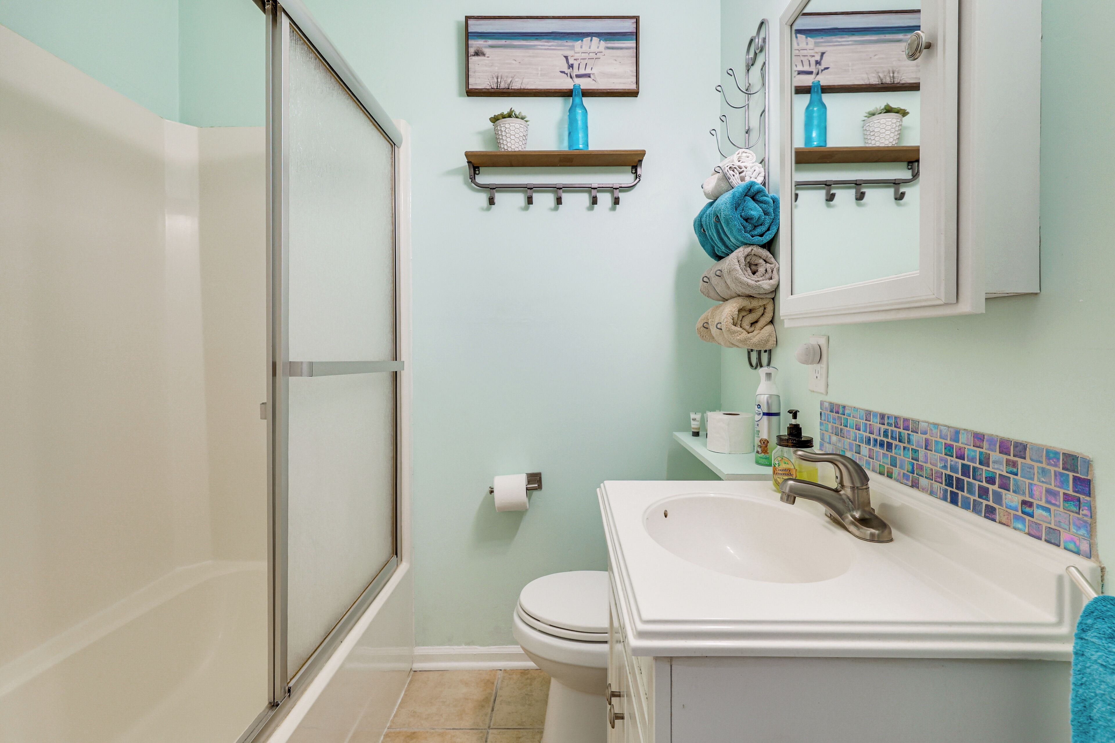 A bathroom with a shower, toilet, sink, and towel rack.