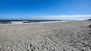 A wide sandy beach with waves crashing onto the shore and a clear blue sky. - Cozy Carolina Beach Condo w/ Ocean Views! (Carolina Beach)