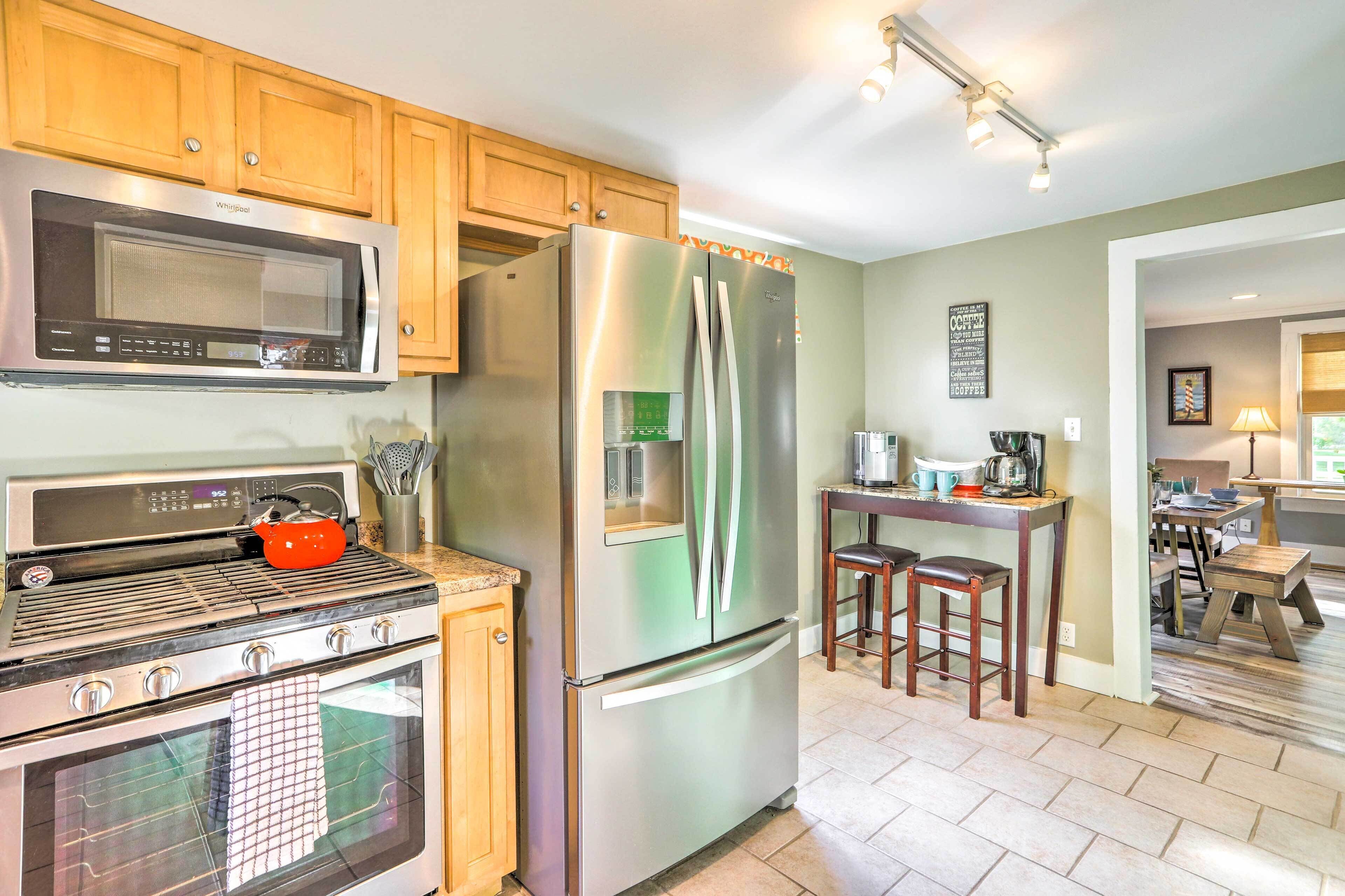 A modern kitchen with stainless steel appliances, wooden cabinets, and a dining area with a table and chairs.
