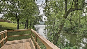 A wooden deck overlooking a calm river with trees on either side. - Mountain Home Cottage w/ Deck on White River! (Gassville)