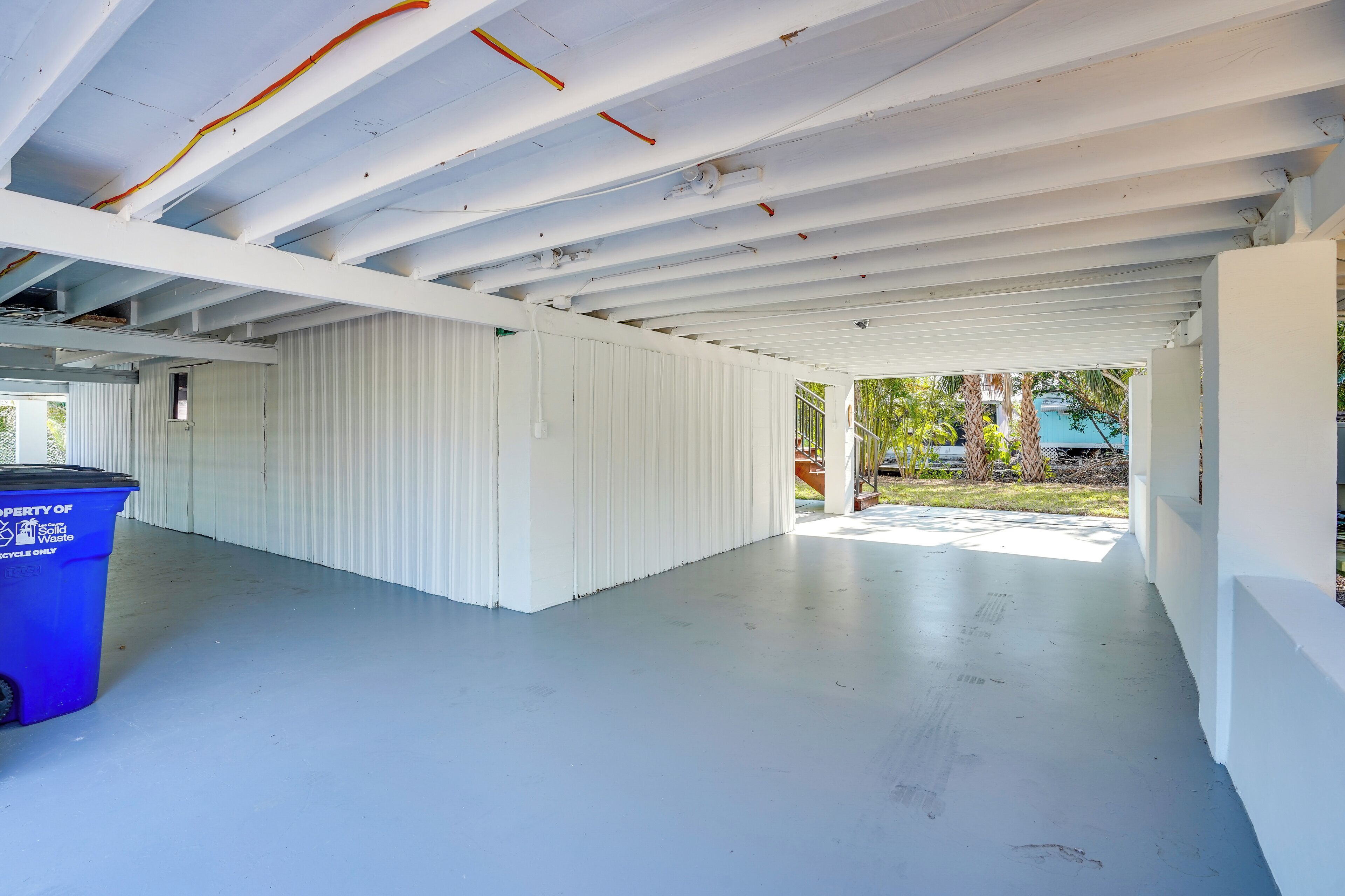 Un espace intérieur avec un plafond haut, des murs blancs et une poubelle bleue.
