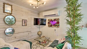 A cozy living room with a wooden wall, a flat-screen TV, a round mirror, and a decorative wall piece. - 'the Goat Hut' Studio Casita: 11 Mi to Strip! (Las Vegas)