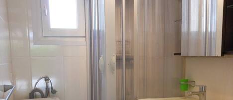 A compact bathroom with a shower enclosure, a sink, and a toilet.