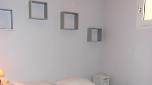 A bedroom with a bed, a nightstand, a lamp, and three wall-mounted picture frames. - APT 2 ROOMS 27m2 + TERRACE 22m2 REF 4015 (MARSEILLAN PLAGE)