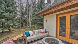 A wooden deck with a sofa, a fire pit, and a chair. - Serene Sun Valley Home w/ Hot Tub & Mtn Views (Sun Valley)