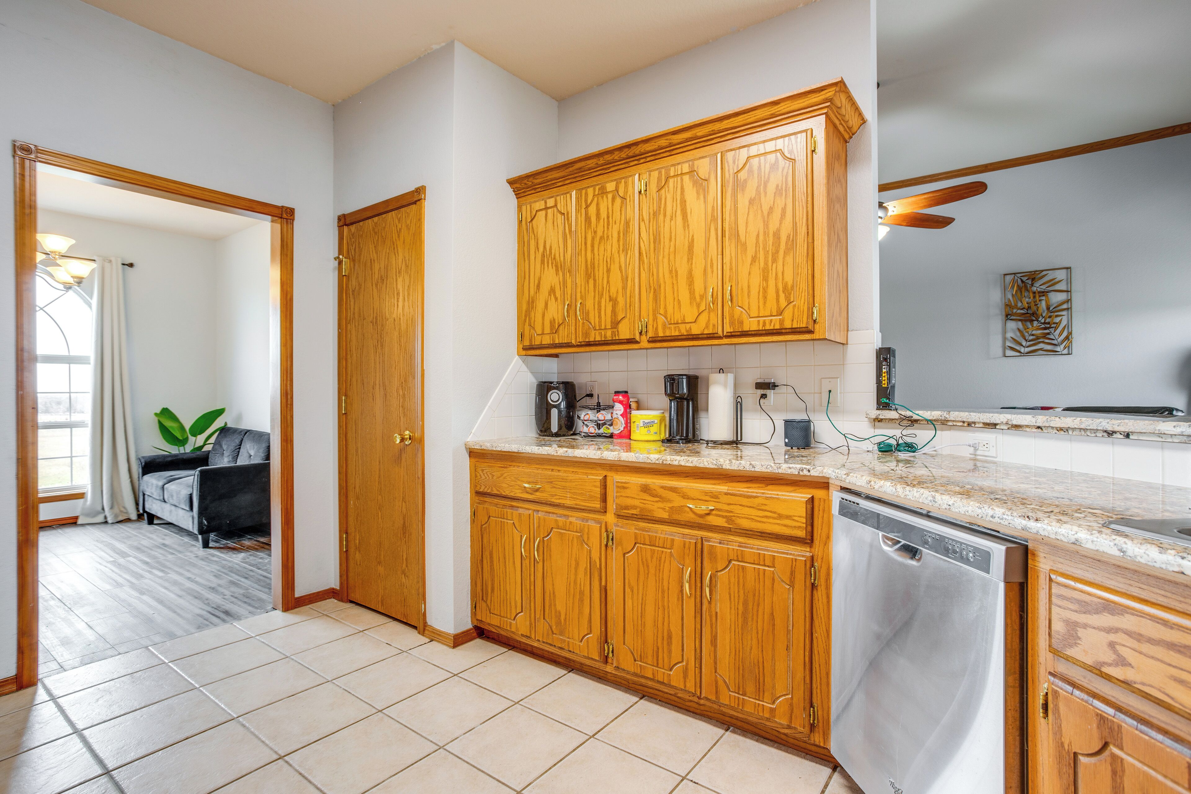 A kitchen with wooden cabinets, a dishwasher, and a countertop with various appliances.