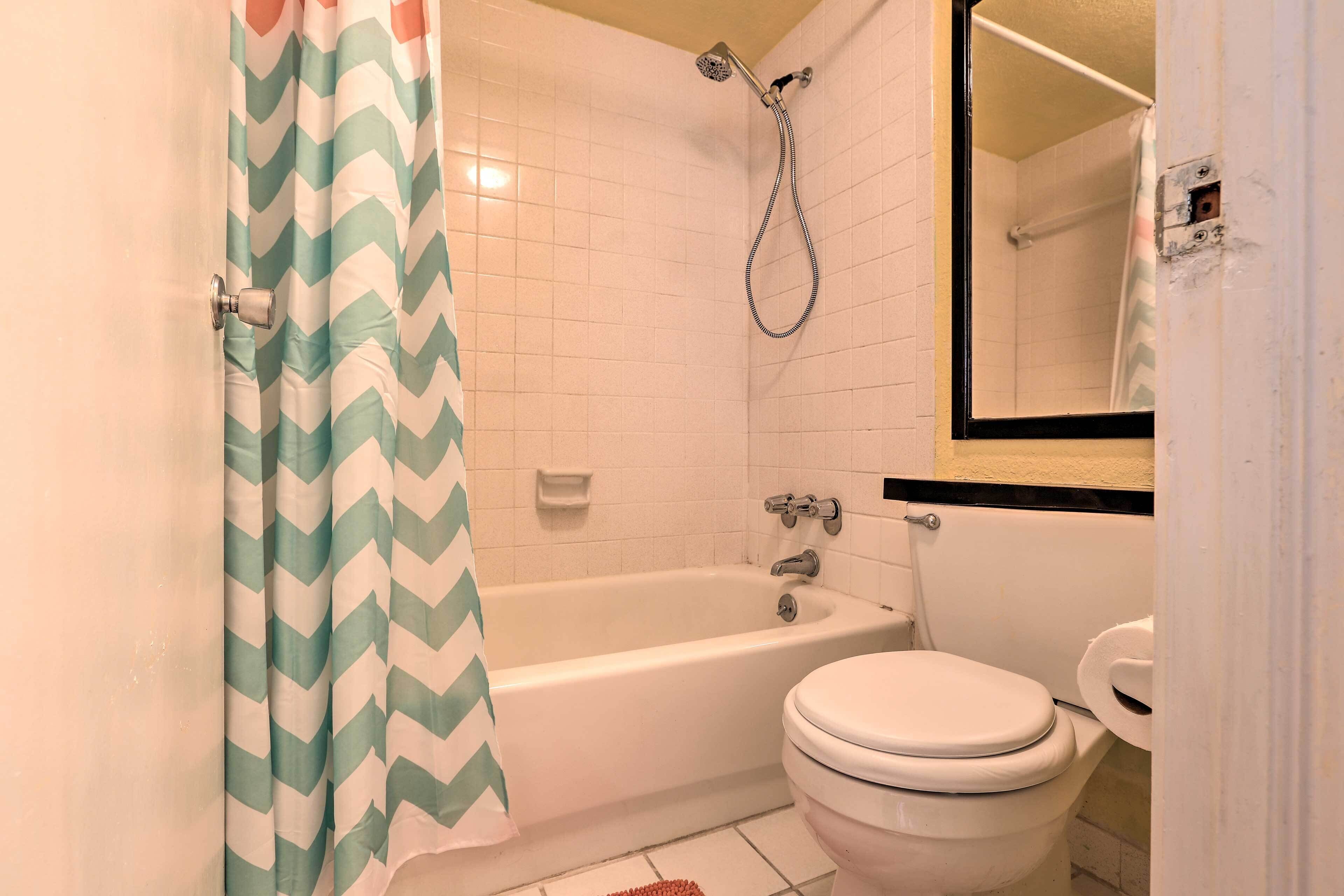 A bathroom with a white bathtub, a toilet, and a showerhead.