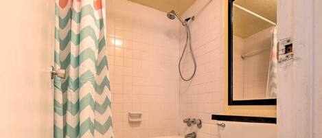 A bathroom with a white bathtub, a toilet, and a showerhead.