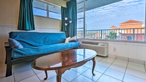 Ein Zimmer mit einem blauen Sofa, einem runden Tisch und einem großen Fenster mit Vorhängen.