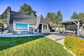 A modern house with a stone chimney, a large window, and a covered outdoor area.