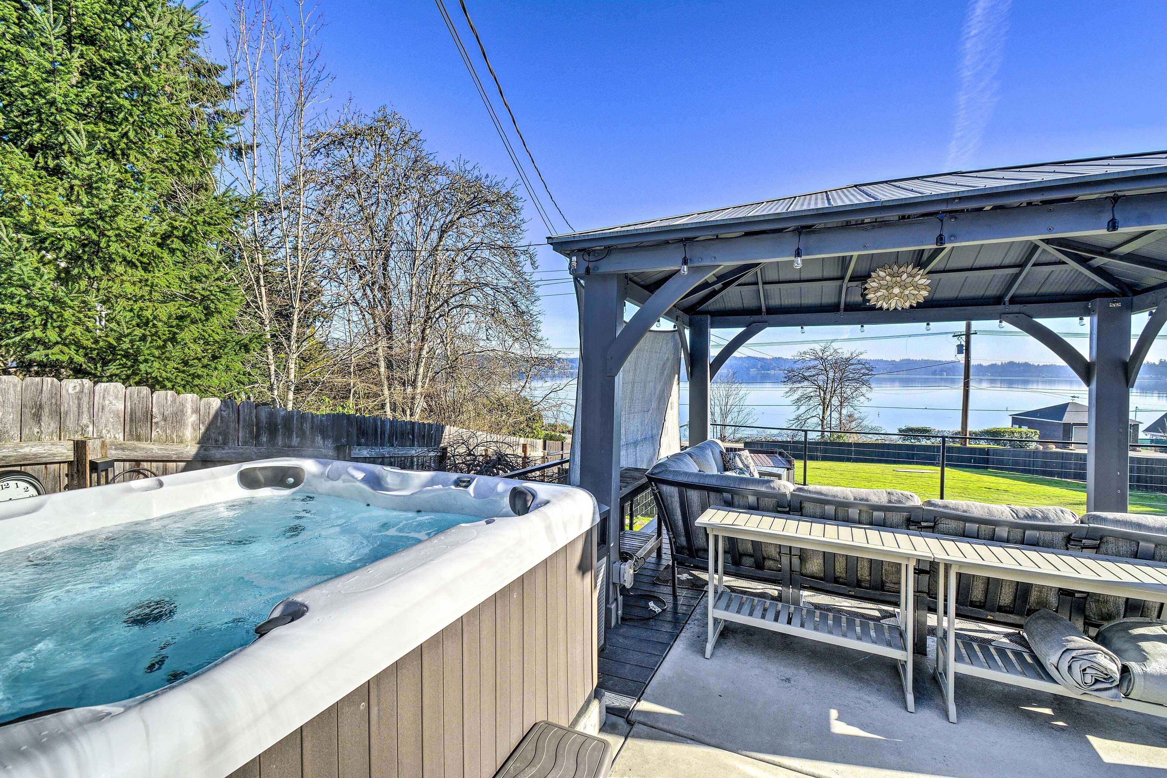 A hot tub and outdoor seating area with a view of a lake.