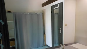 A bedroom with a bed, a bathroom with a shower curtain, and a door with a mirror. - VILLA  3 ROOMS MEZ 47m2 + TERRACE 15m2 REF 4004 (MARSEILLAN PLAGE)