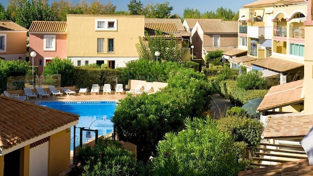 A residential area with a swimming pool surrounded by greenery and multiple buildings with tiled roofs. - VILLA  3 ROOMS MEZ 47m2 + TERRACE 15m2 REF 4004 (MARSEILLAN PLAGE)