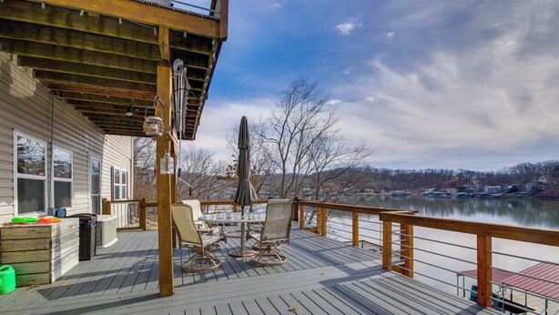 A wooden deck with outdoor furniture, a covered area, and a view of a lake. - Gravois Mills Home: Boating Vacation! (Gravois Mills)